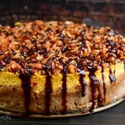 baked pumpkin cheesecake topped with pecans and chocolate drizzle.