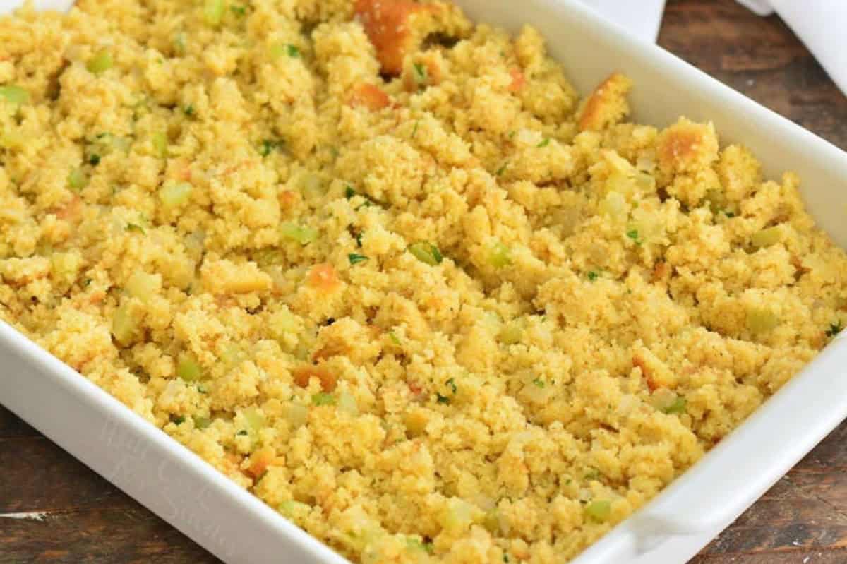 unbaked cornbread dressing spread in a white baking dish.