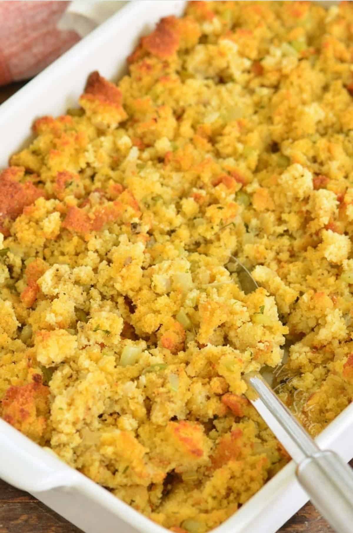 fluffing cornbread dressing with a serving spoon.