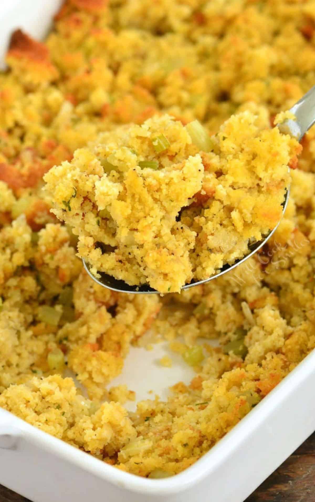 scooping out some cornbread dressing with a silver serving spoon.