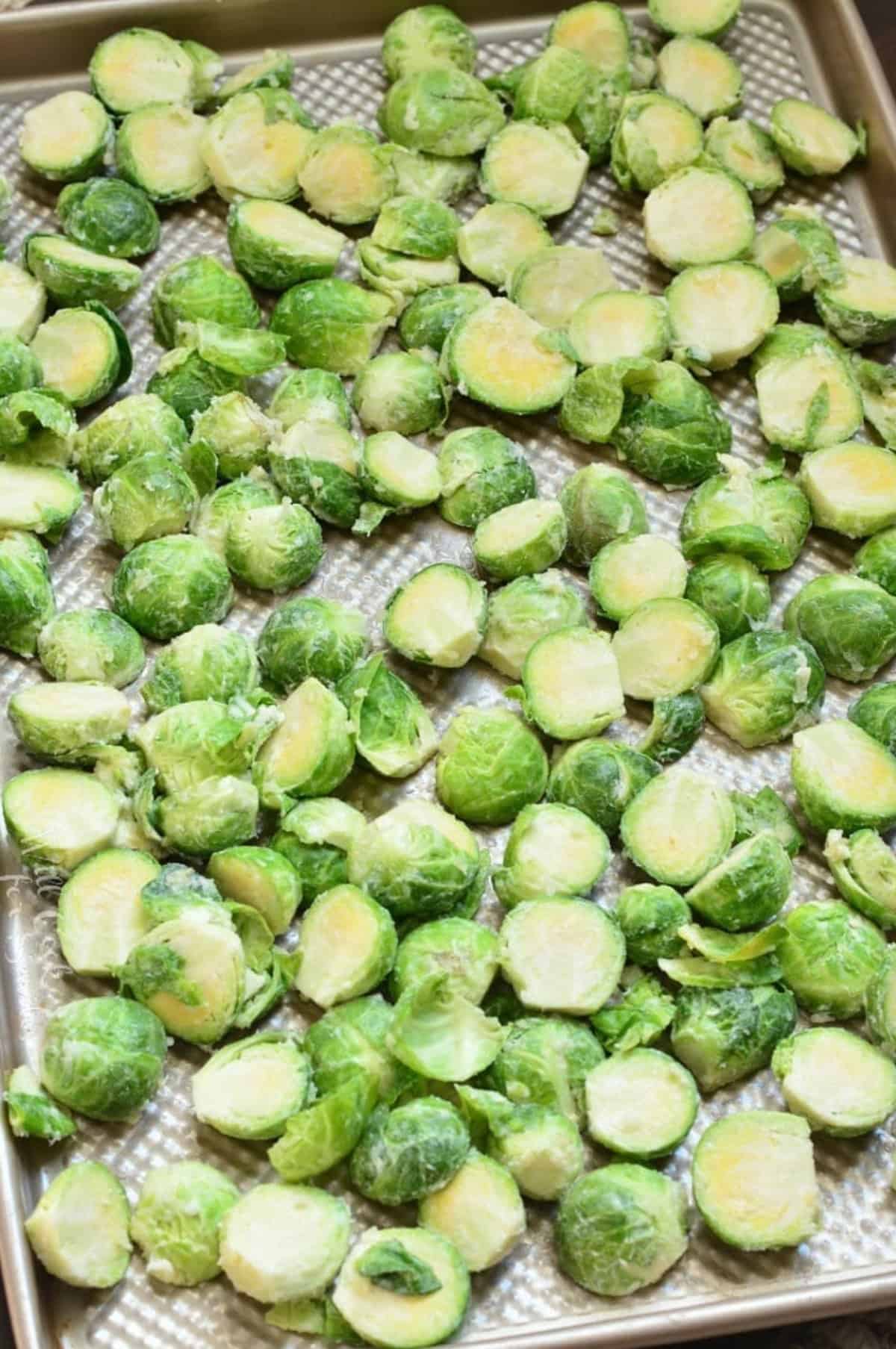 Uncooked brusssels sprouts on a baking sheet.