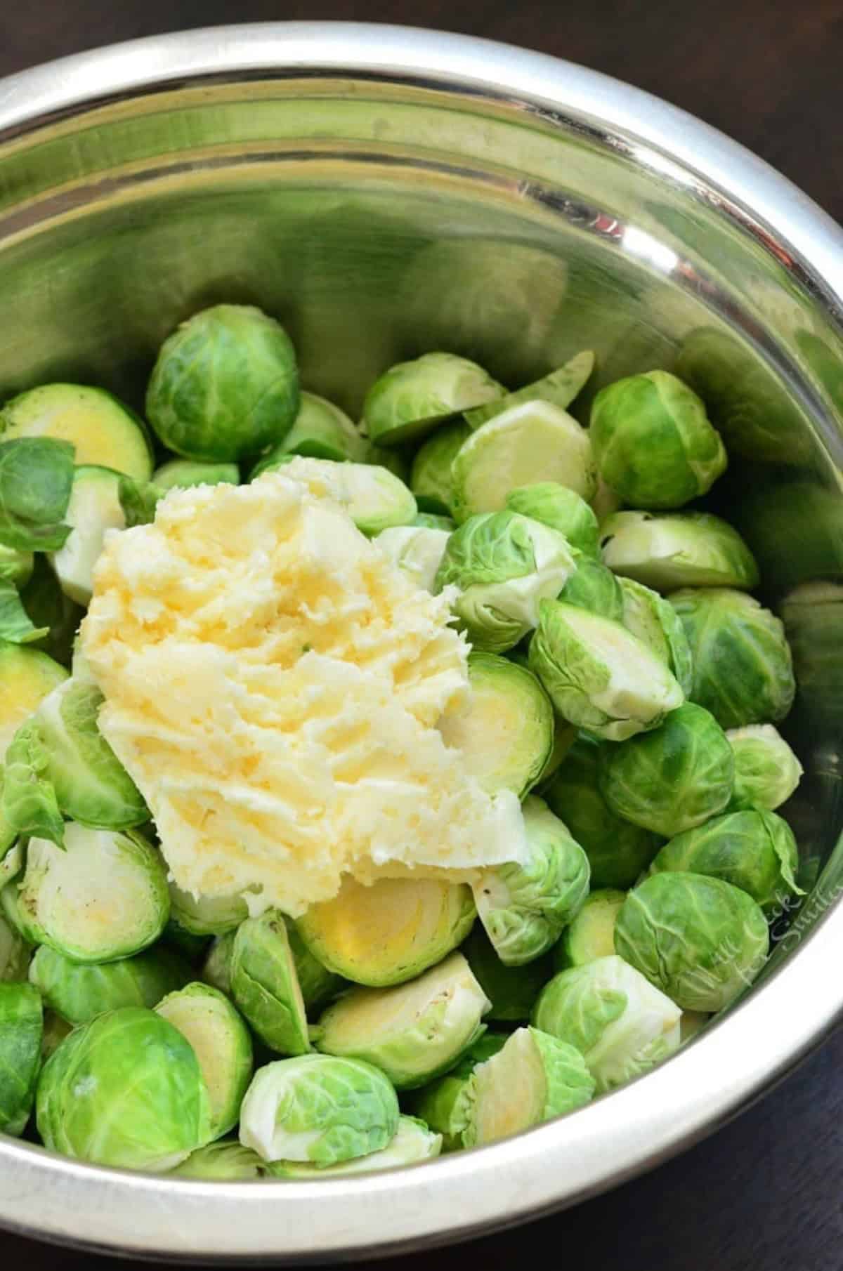 A metal bowl of brussel sprouts with garlic butter on top.