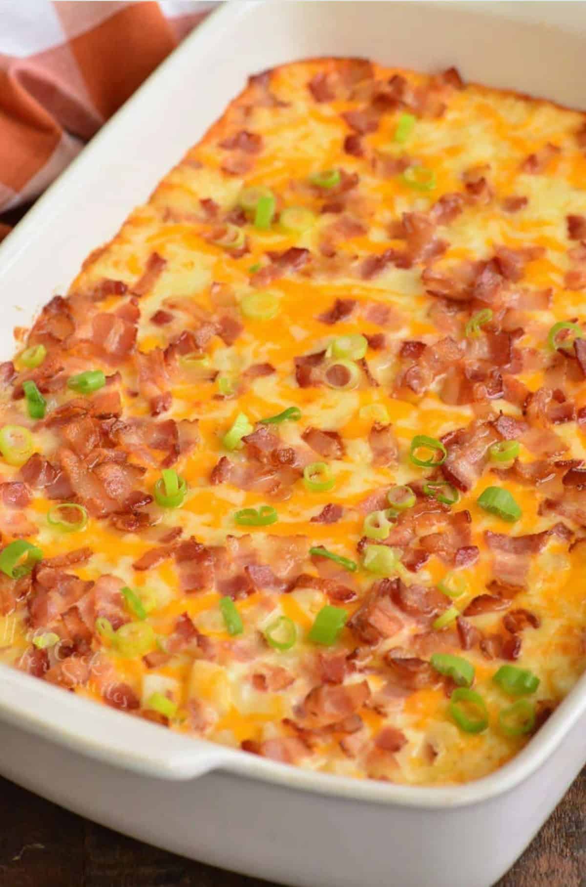 Loaded cheesy potato casserole baked with bacon and green onions on top.