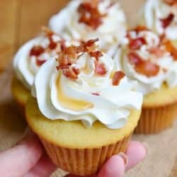 holding one maple bacon cupcake with buttercream frosting.