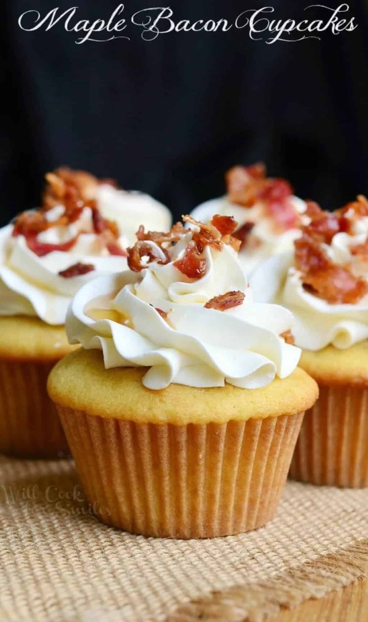 maple bacon yellow cake cupcakes topped with swirled buttercream frosting, bacon, and maple syrup.