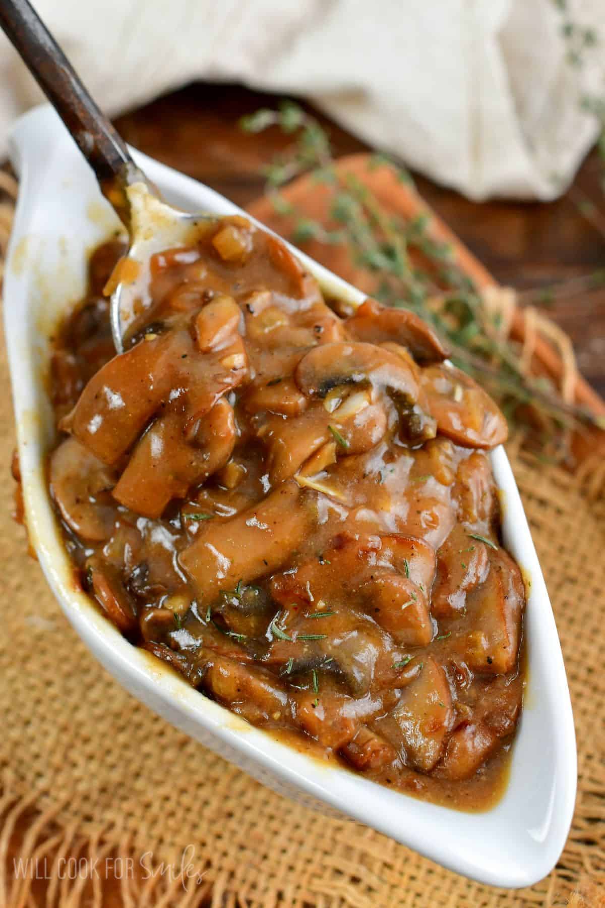 spooning mushroom gravy in a white gravy boat.