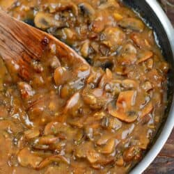 scooping mushroom gravy with a wooden spoon from the cooking pan.