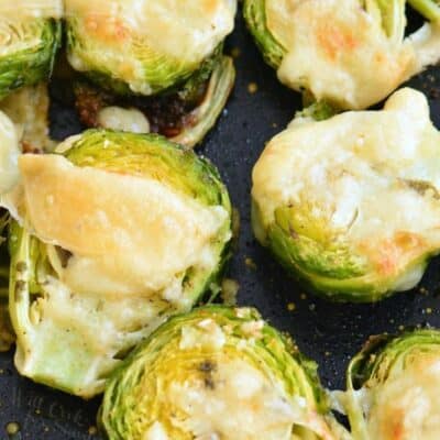 Brussels sprouts on a baking sheet with melted parmesan on top.