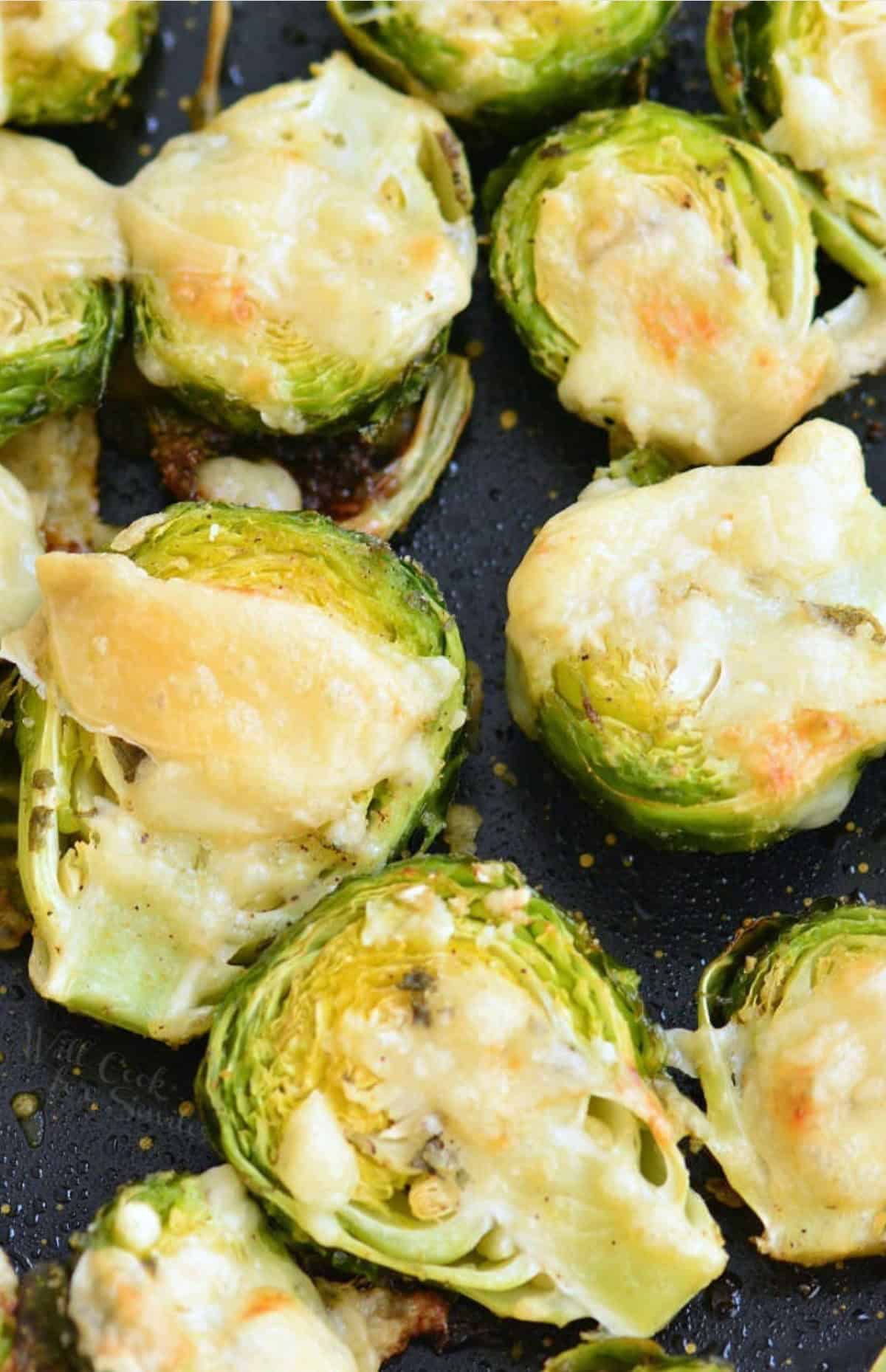 Brussels sprouts on a baking sheet with melted parmesan on top.