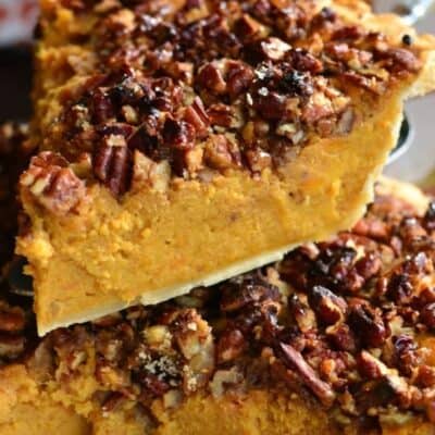 a slice of sweet potato pie with crunchy pecan topping on top of a whole pie.