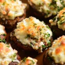 sausage stuffed mushroom garnished with parsley in the baking dish and other visible.