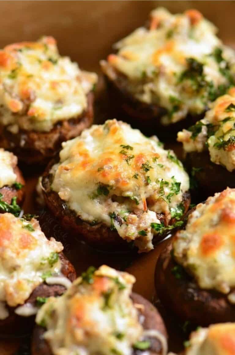 sausage stuffed mushroom garnished with parsley in the baking dish and other visible.