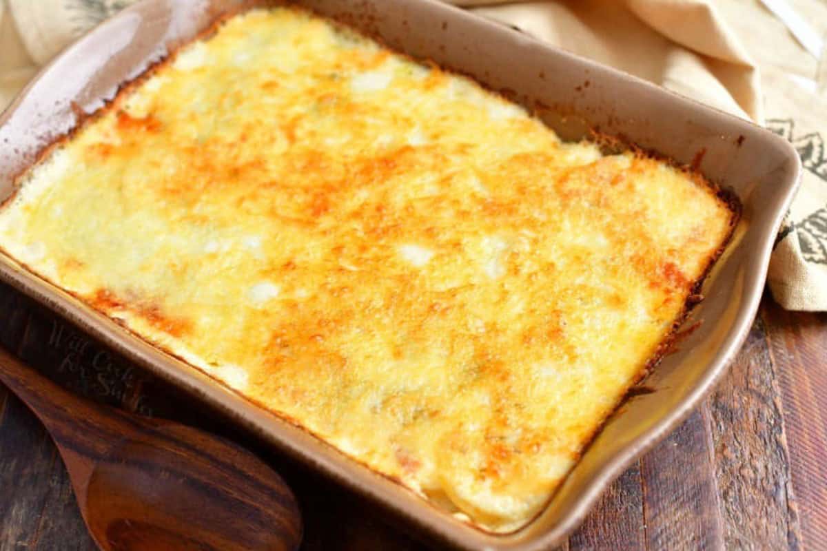 Cooked scalloped potatoes in a baking dish on a wood surface.