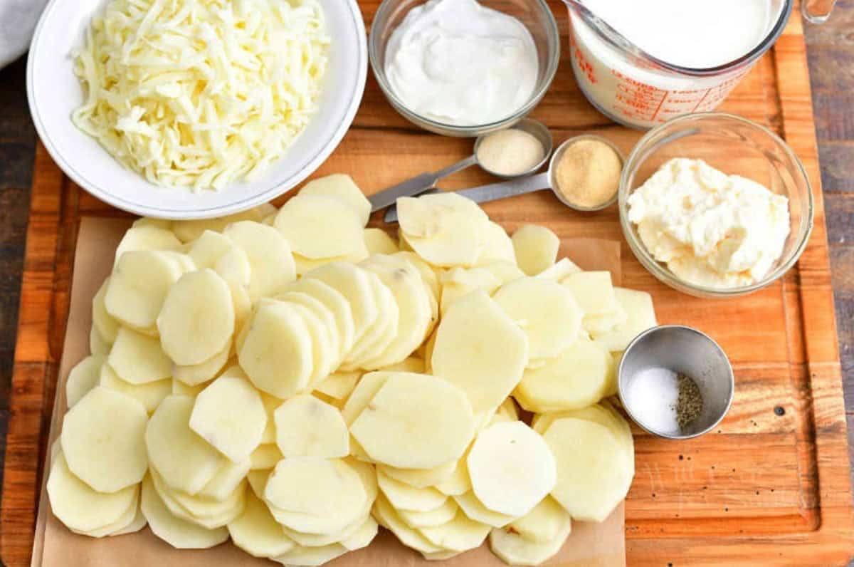 ingredients for scalloped potatoes on a wood cutting board.