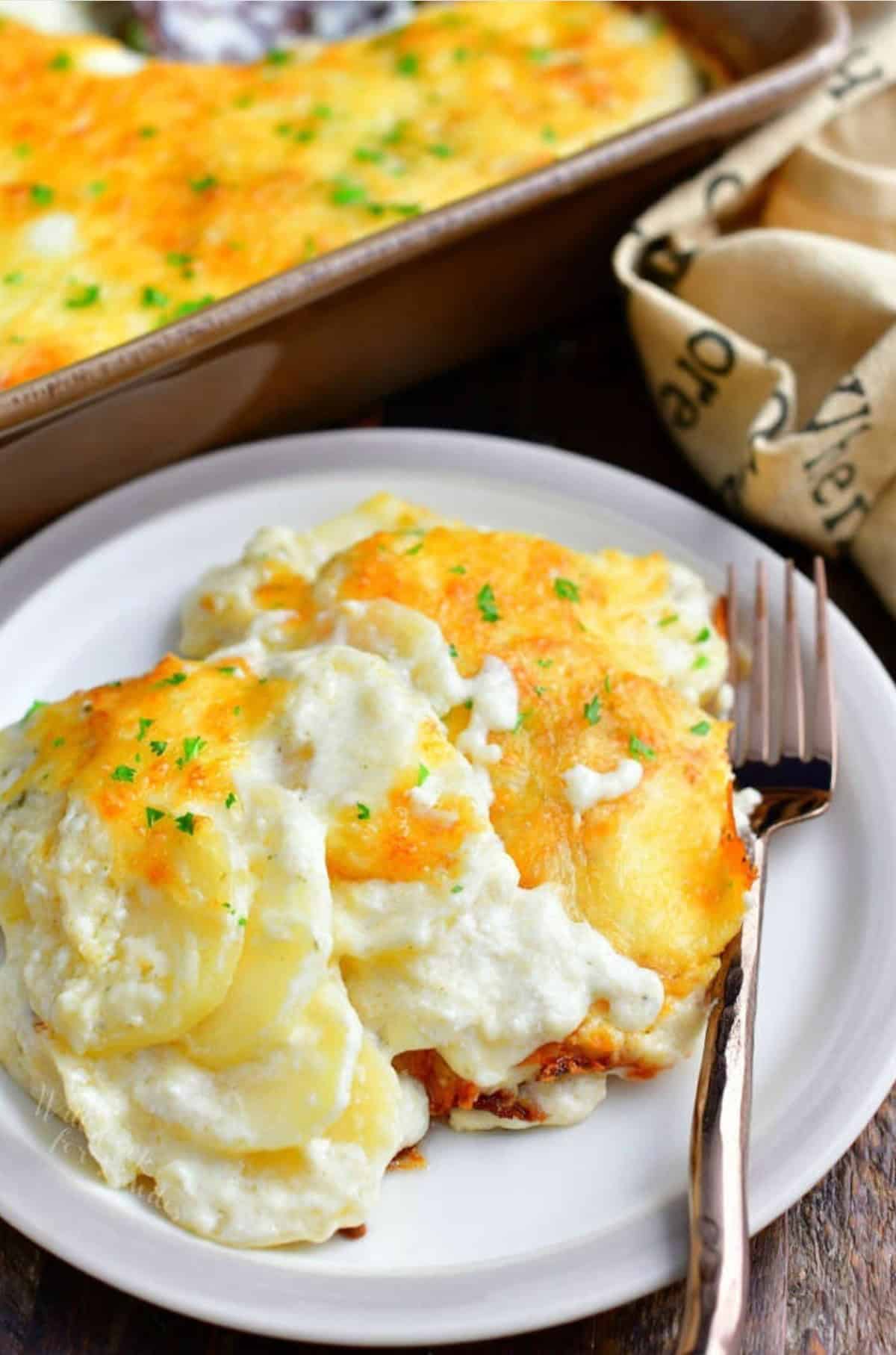 scalloped potatoes on a plate with a fork to the right.