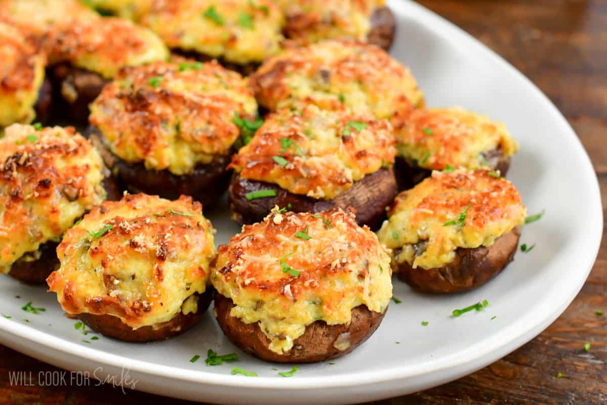 stuffed mushrooms side by site on a white platter with green garnish.