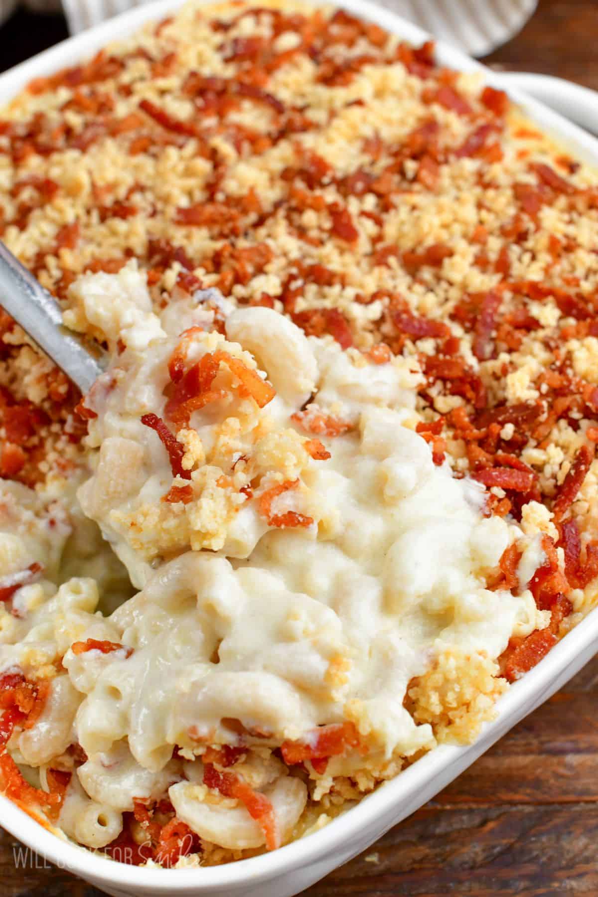 gooey cheesy mac and cheese in a baking dish with a spoon.