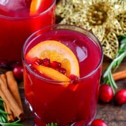 Christmas punch in a glass topped with orange and pomegranate seeds.