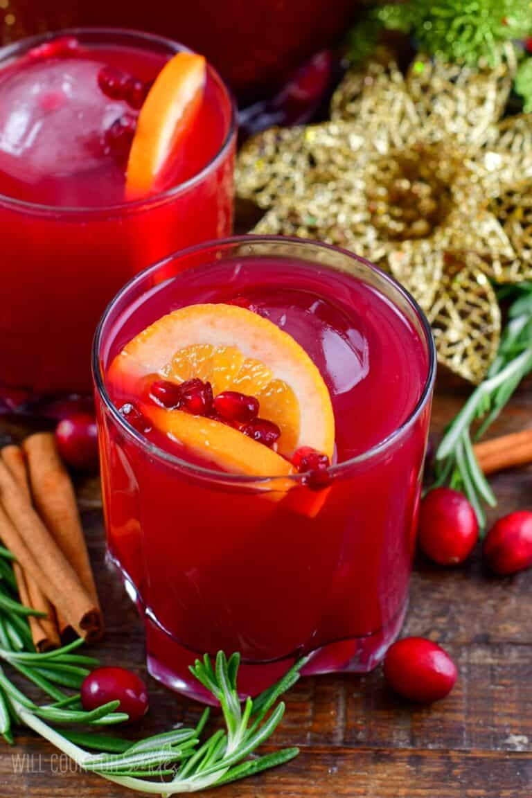 Christmas punch in a glass topped with orange and pomegranate seeds.