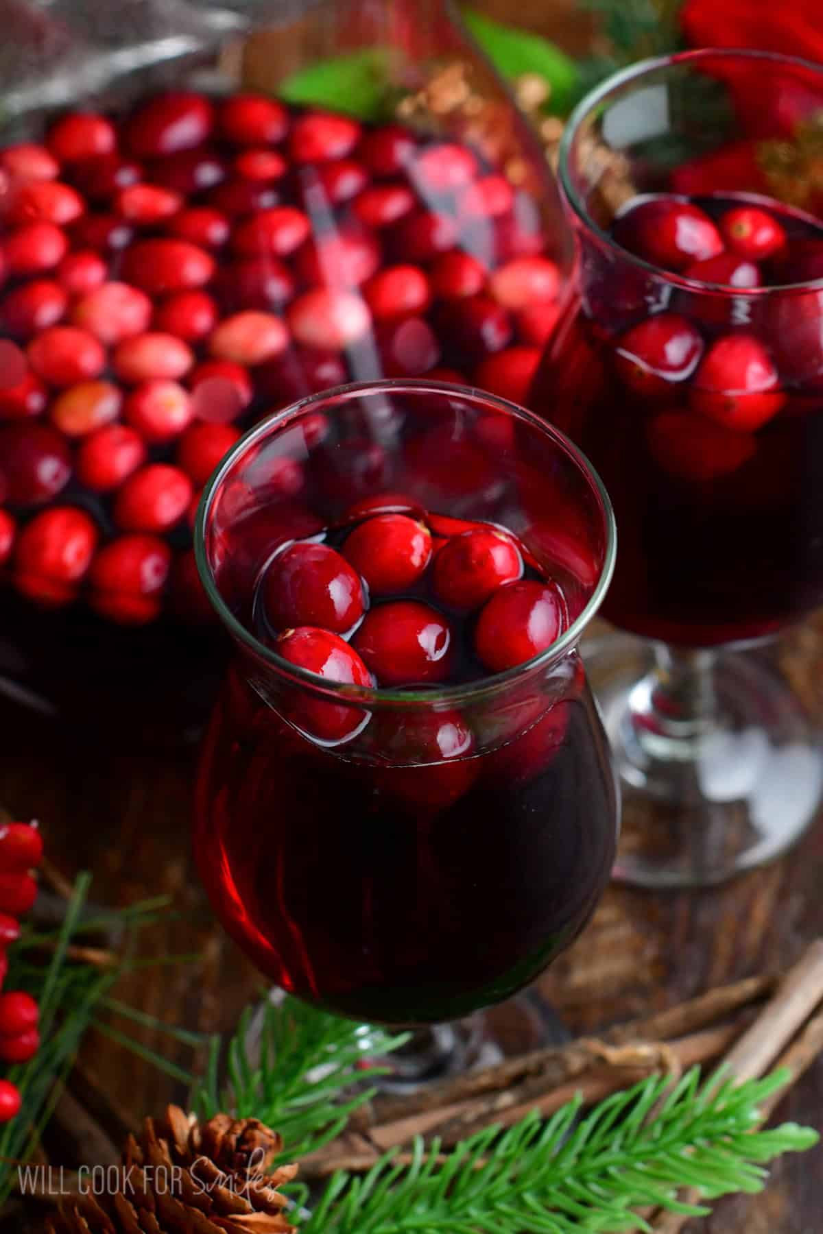 wine glass full of the cranberry sangria with some cranberries in it.