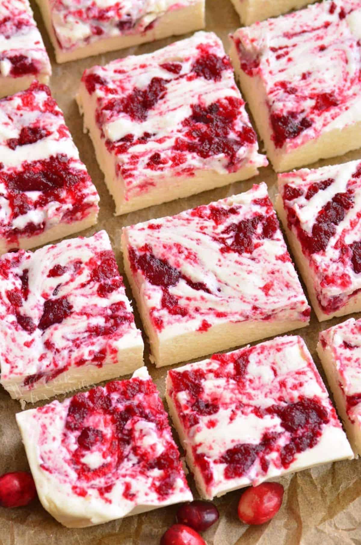 Cranberry White chocolate fudge cut into squares on parchment.