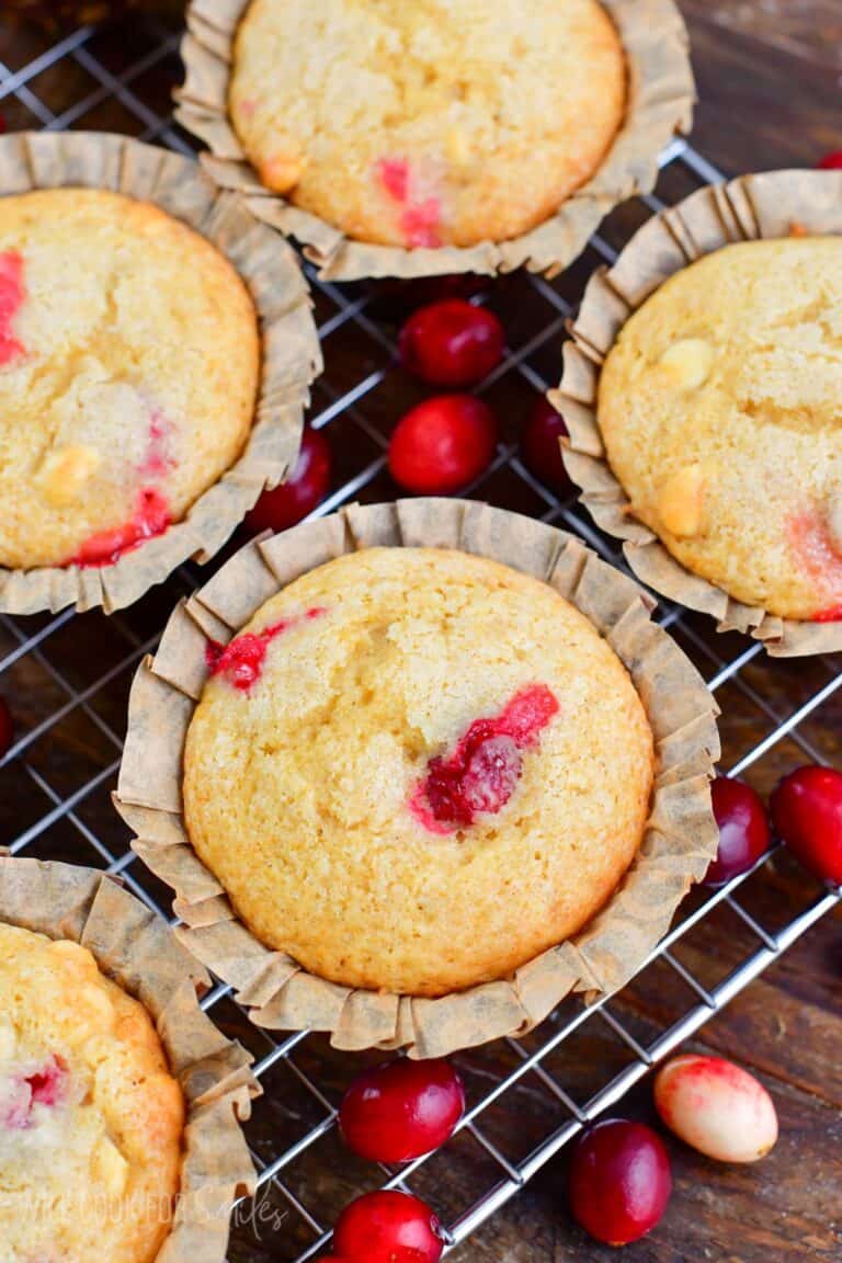 cranberry muffin in parchment muffin cup with some more muffins visible.