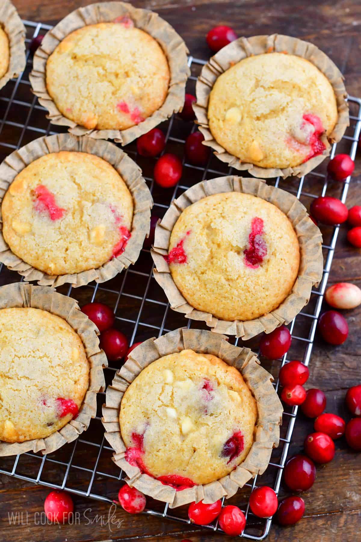 six cranberry muffins on the wire rack surrounded by fresh cranberries.