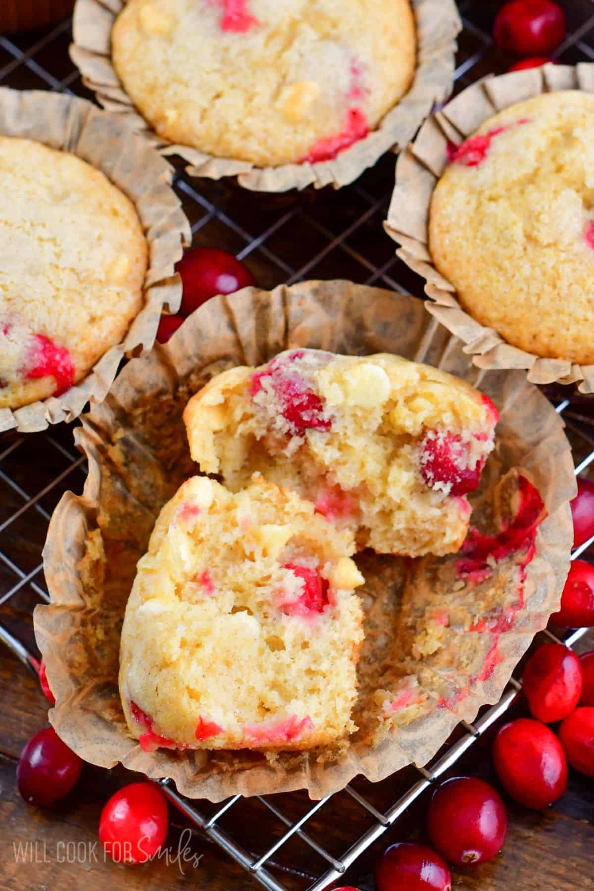 cranberry muffin split in half on the parchment paper on a wire rack.