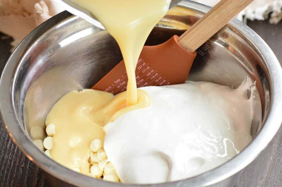 Pouring condensed milk into a bowl for white chocolate fudge.