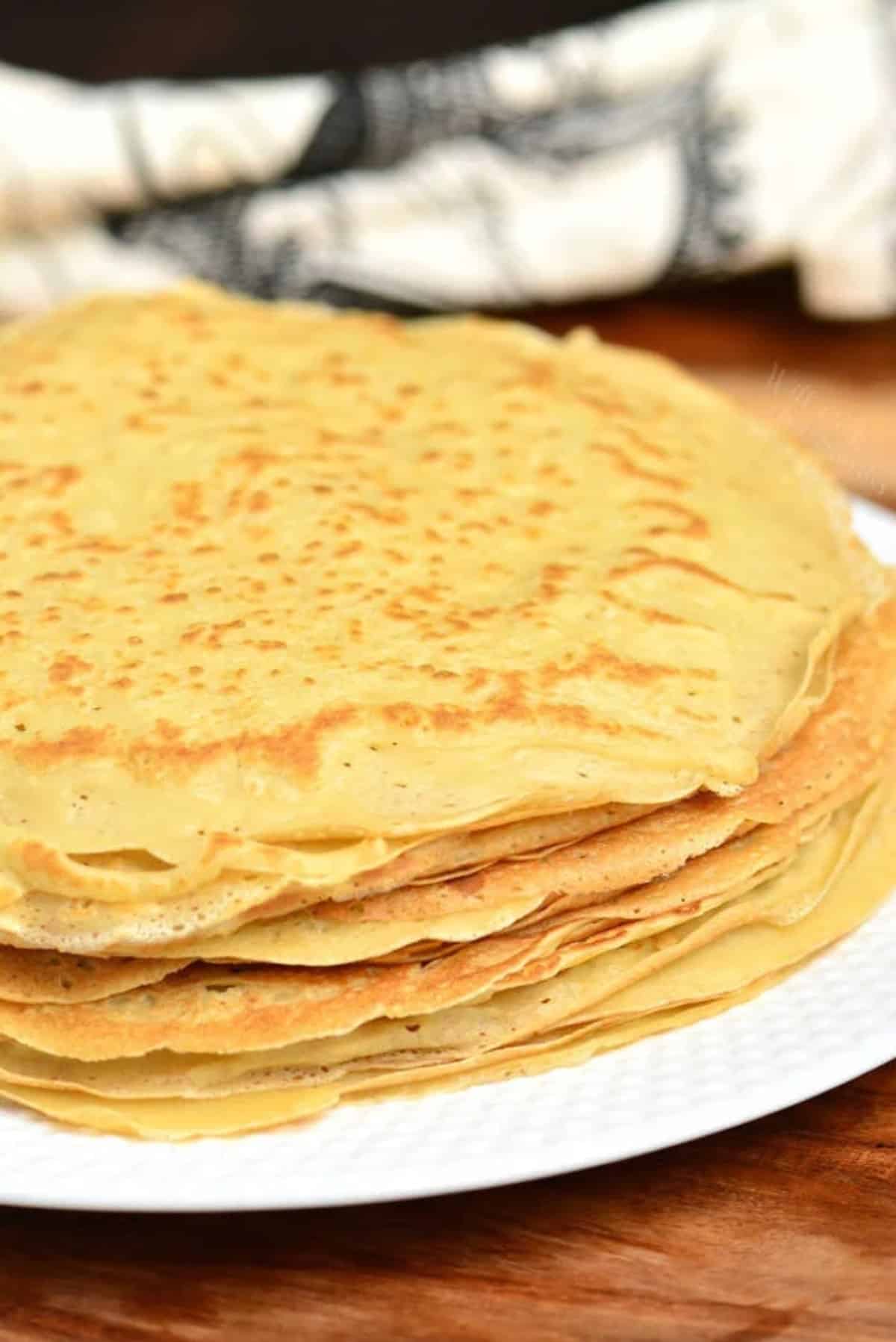 tall stack of crepes on a platter with some towels.