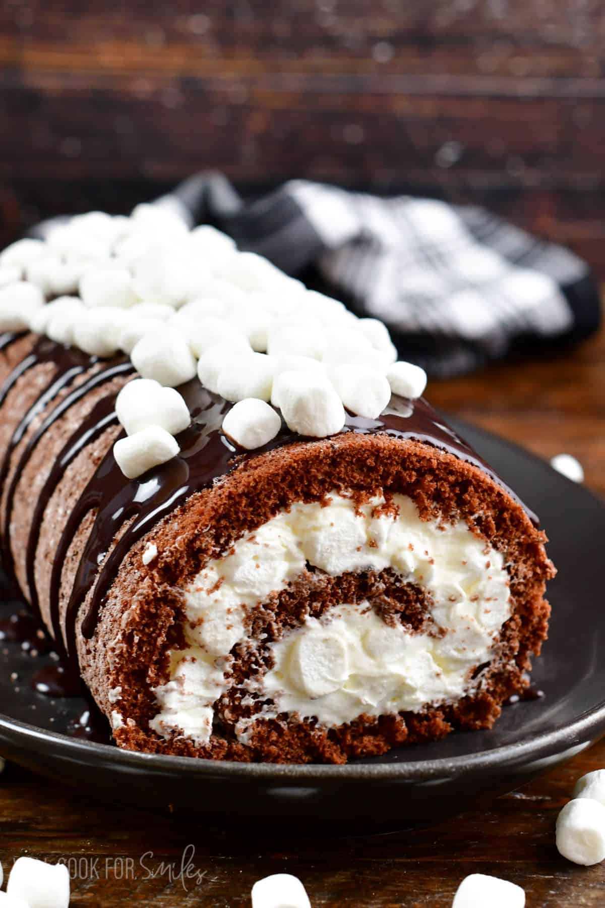 chocolate cake roll with white marshmallow frosting and topped with chocolate and marshmallows.