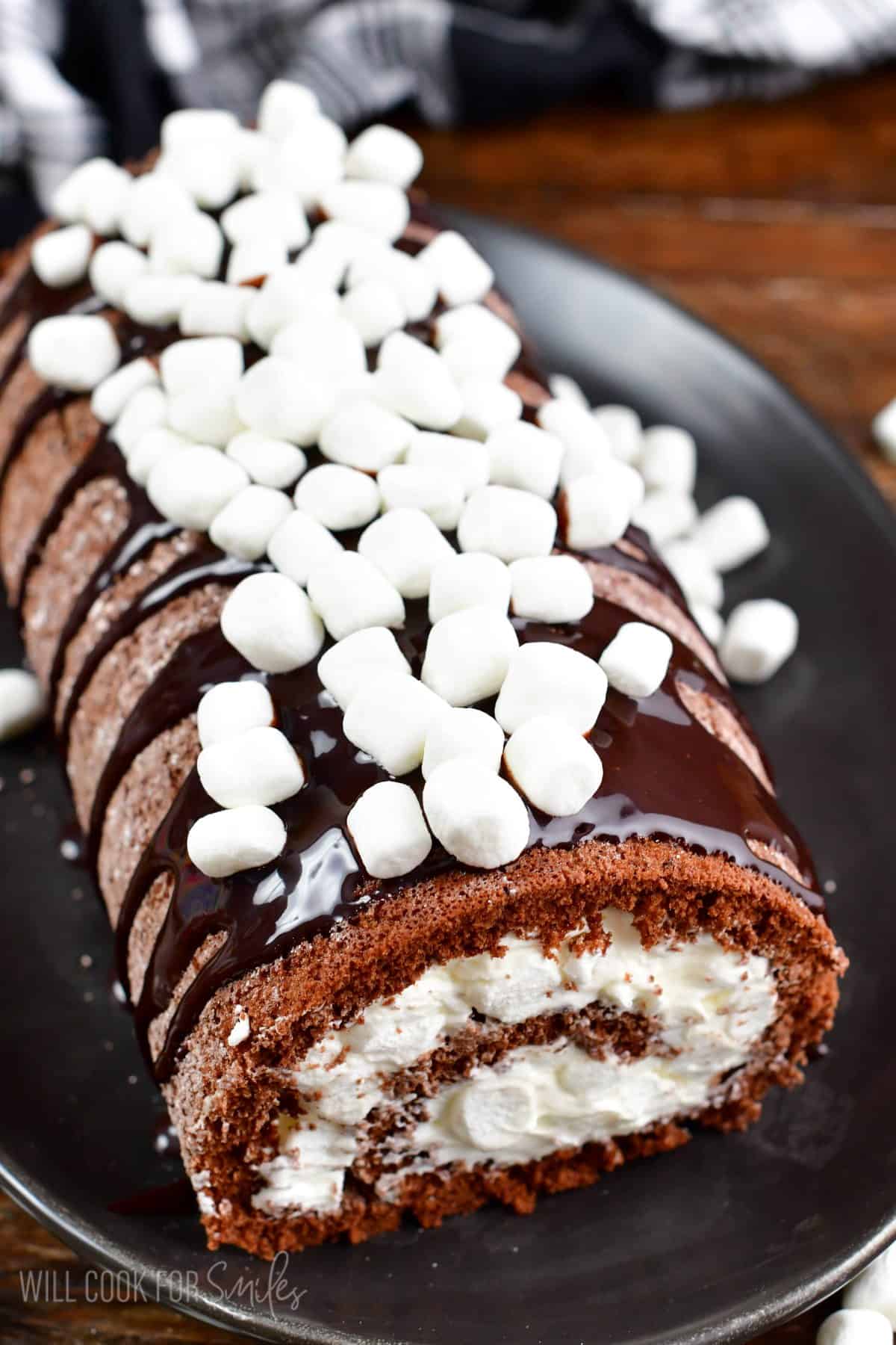 chocolate cake roll with marshmallow frosting and more marshmallows on top.