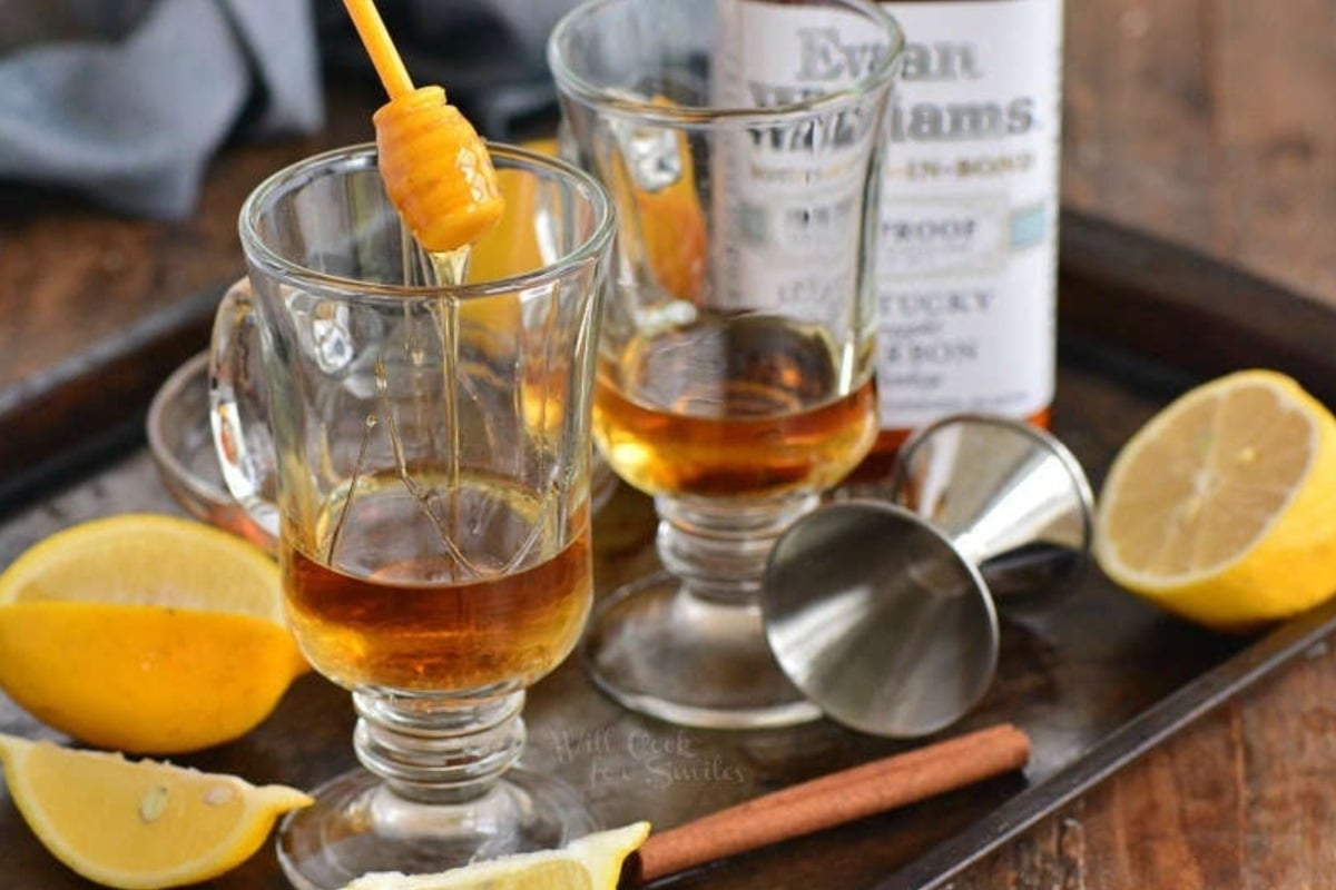 adding honey to a glass mugs with whiskey.