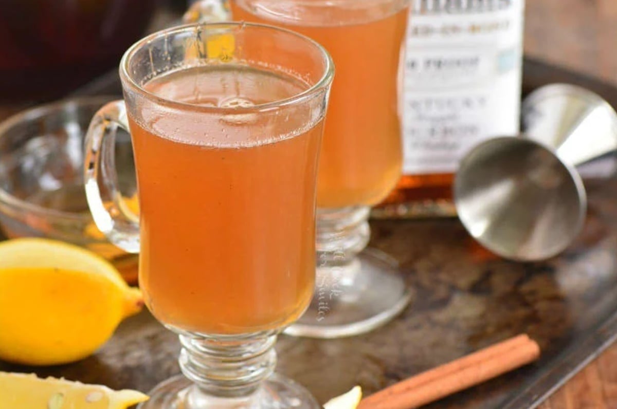 glass mug with hot toddy in it and lemon around.