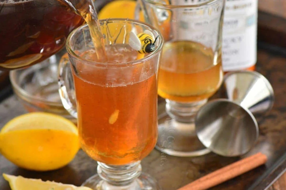 pouring in tea into glass mug to make hot toddy.