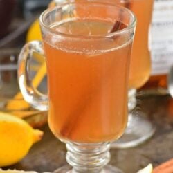 two glass mugs with hot toddies and lemons and cinnamon around.