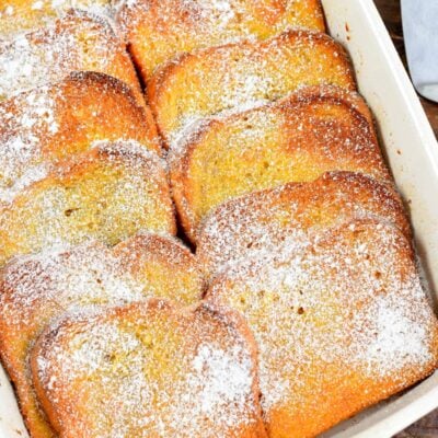 baked French toast casserole in the white baking pan with powdered sugar.