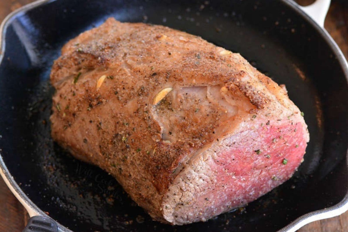 searing the seasoned roast beef in a pan.