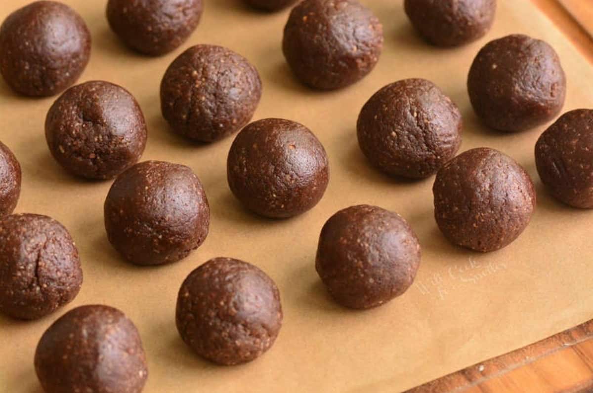 several rolled rum balls on parchment paper without coating.