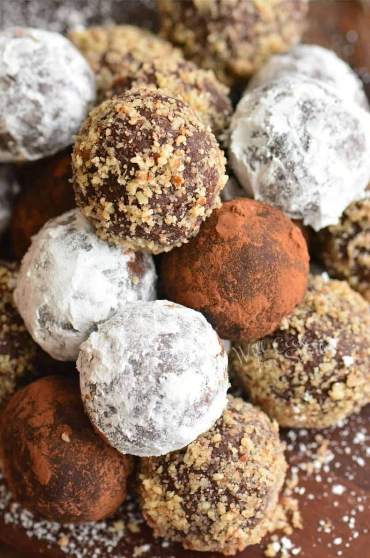 stacked rum balls coated in nuts, cocoa powder, and powdered sugar.