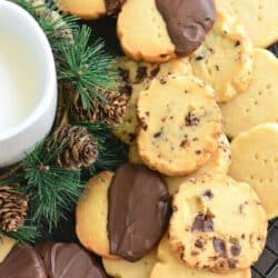 Shortbread cookies plan, dipped in chocolate, and with chocolate chuncks stacked on a wire rack.