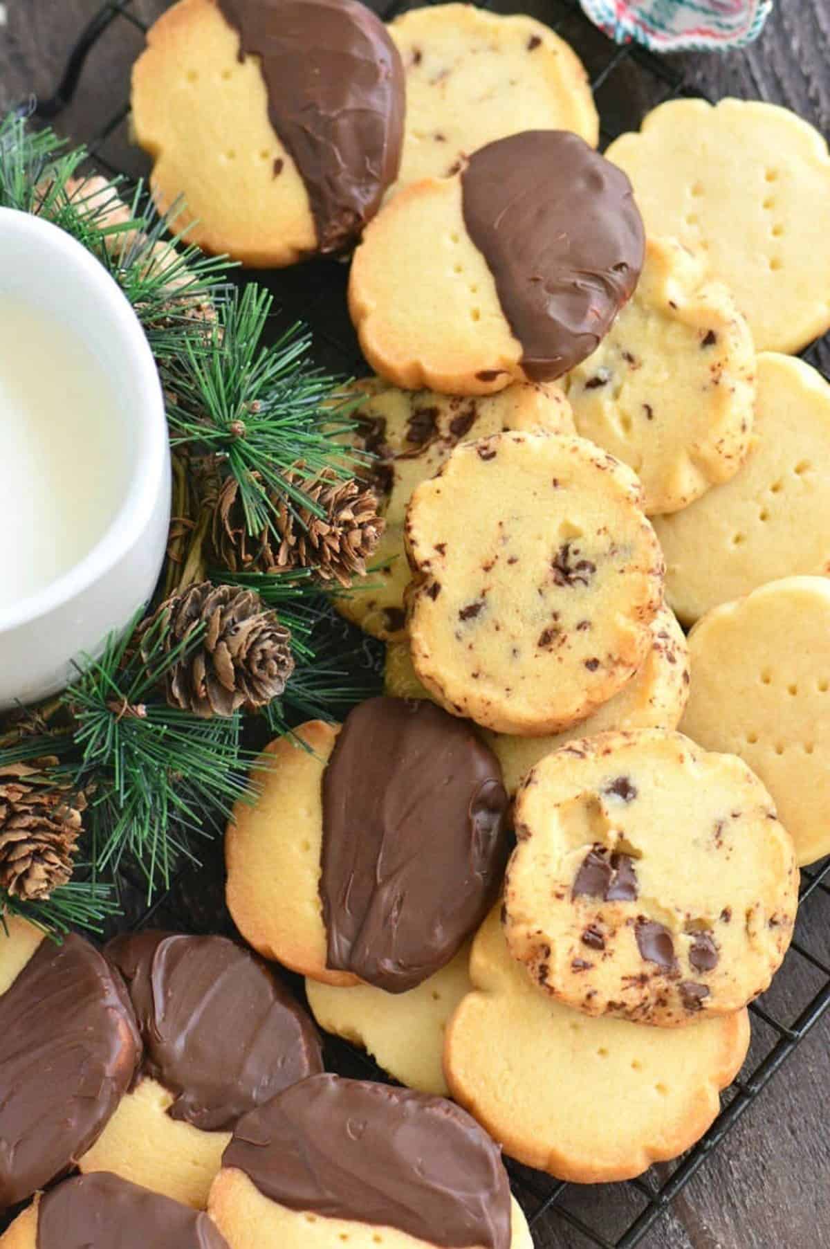 Shortbread cookies plan, dipped in chocolate, and with chocolate chuncks stacked on a wire rack.