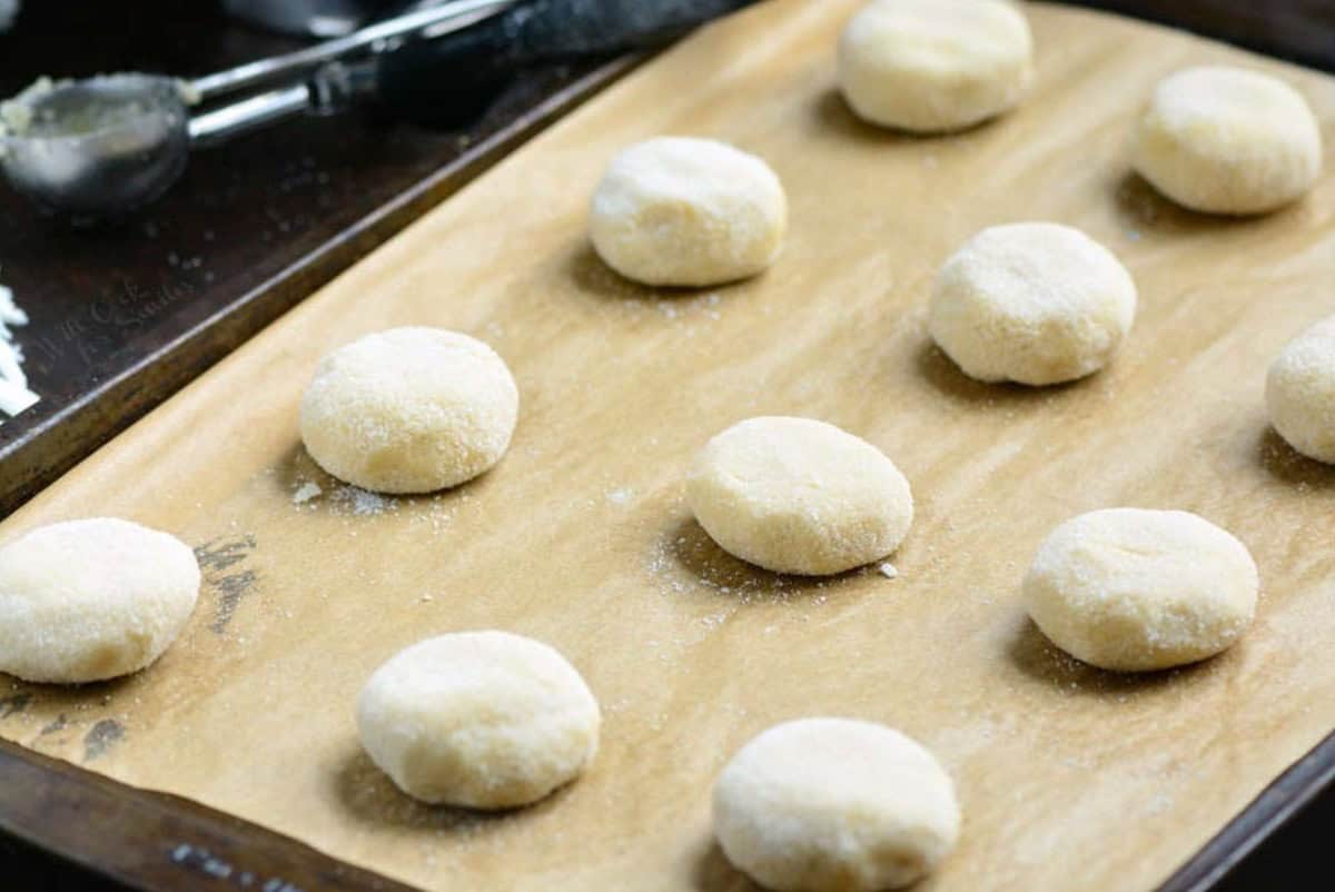 Raw sugar cookies on a parchement lined baking sheet.