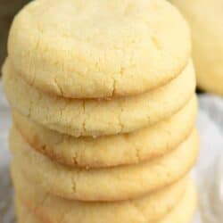 Sugar cookies stacked up on top of each other on wax paper.