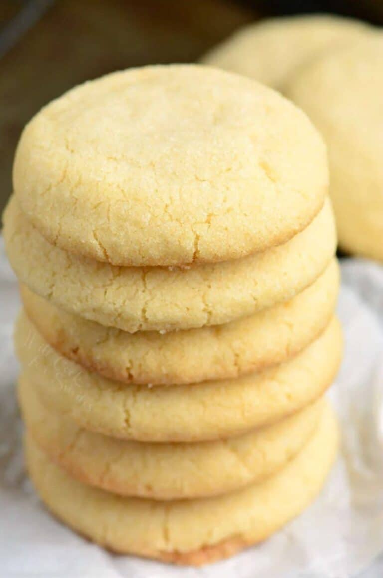 Sugar cookies stacked up on top of each other on wax paper.