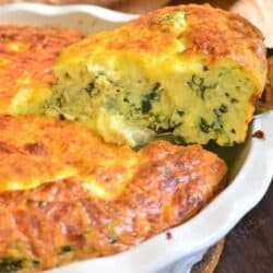 pulling out a slice of spinach artichoke crustless quiche from the baking dish.