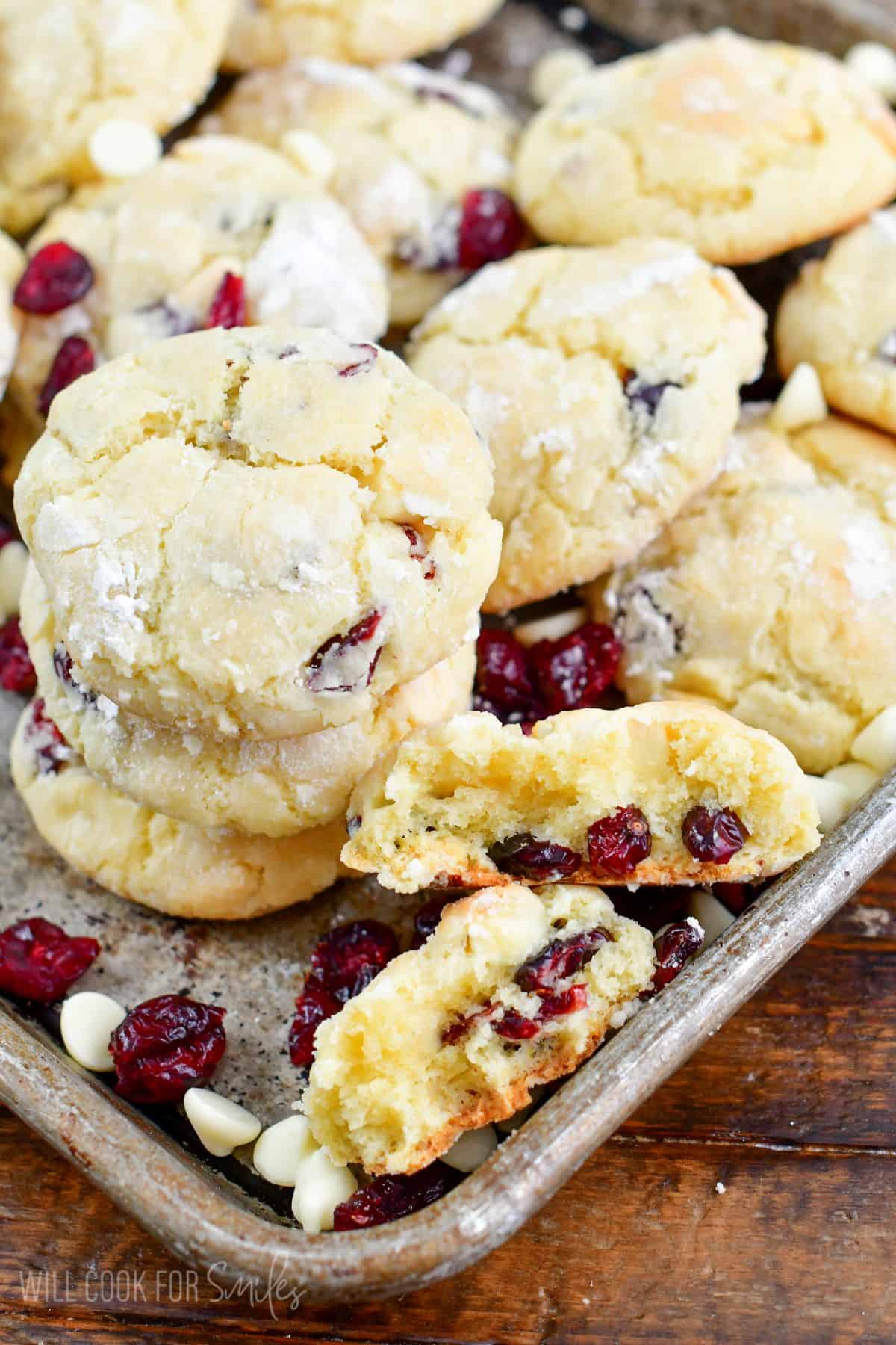 several White Chocolate Cranberry Cream Cheese Cookies stacked and spread around in baking pan.