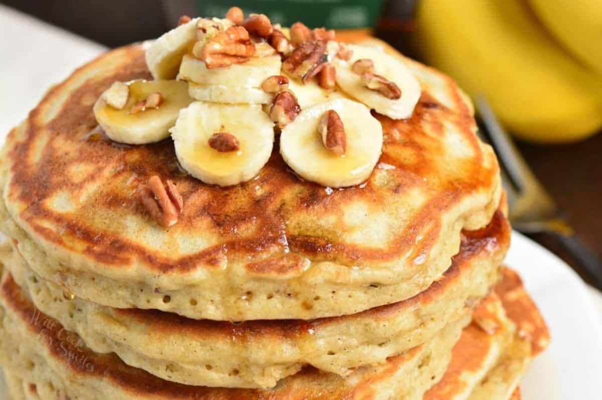 banana pancakes topped with sliced bananas, pecans, and maple syrup.