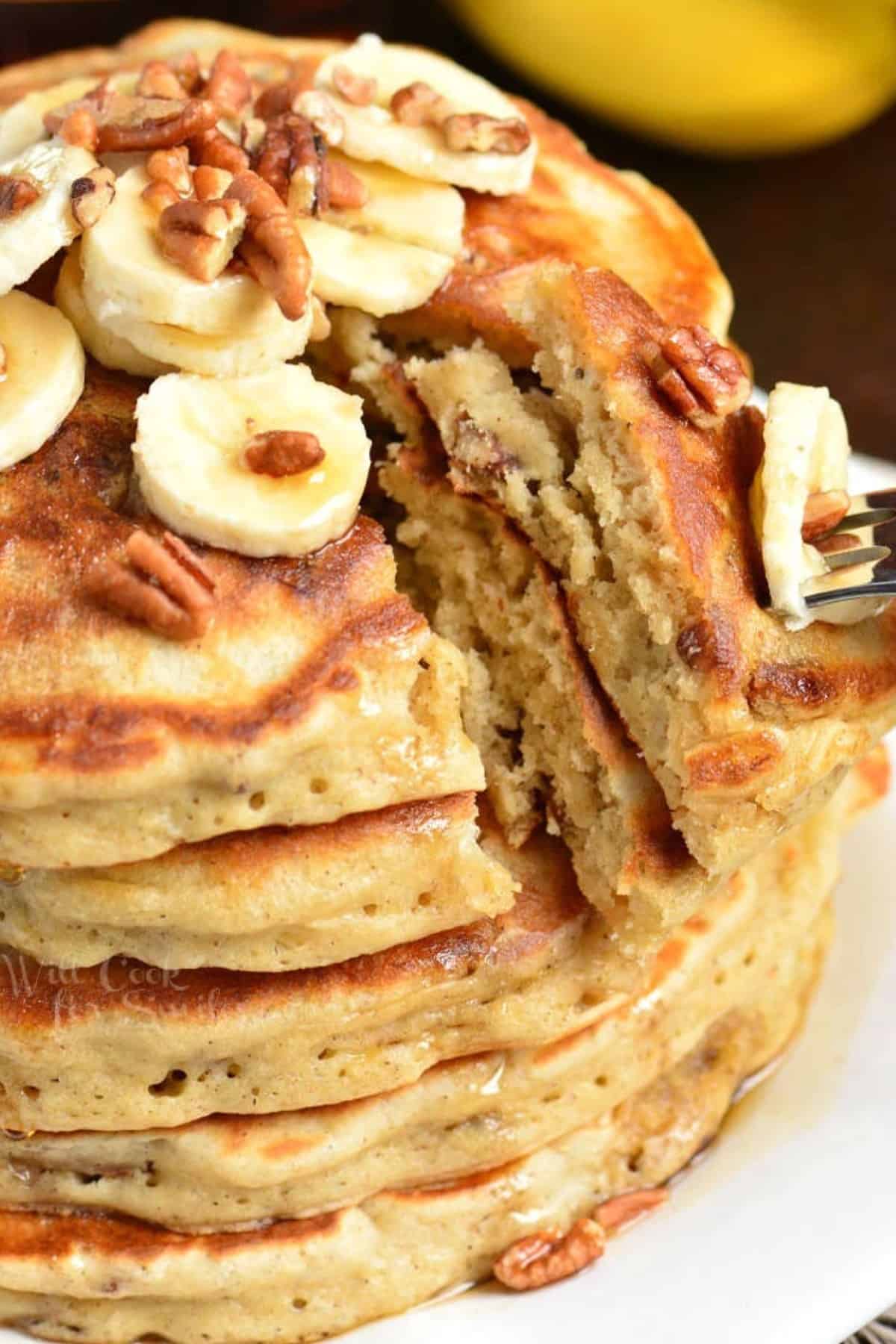 cutting into a stack of pancakes and pulling some slices with a fork.