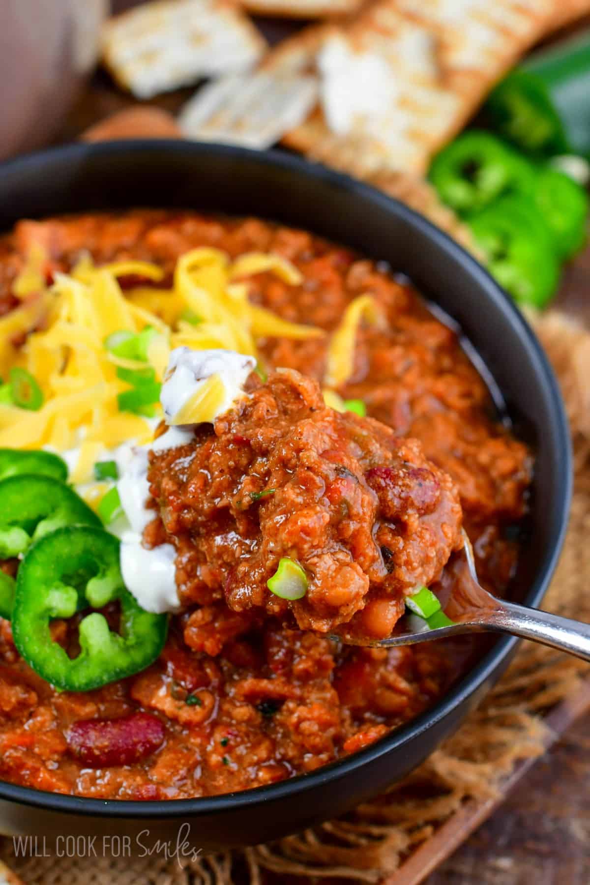 spooning out some beef chili from the bowl with a spoon.